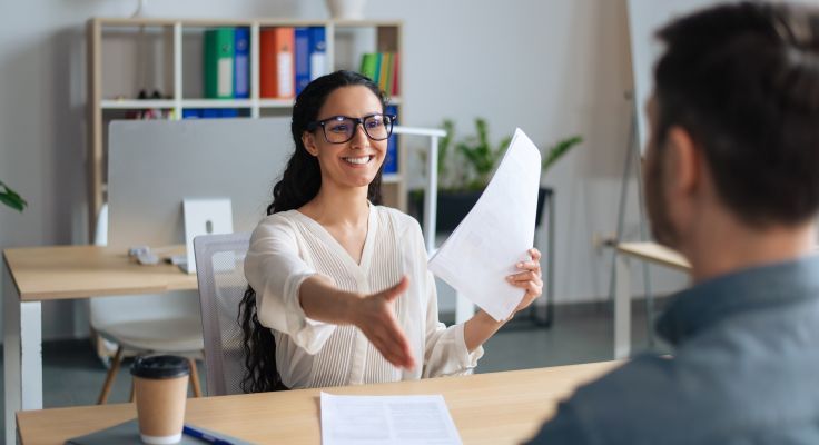 Lächelnde Personalmanagerin überreicht einen Vertrag