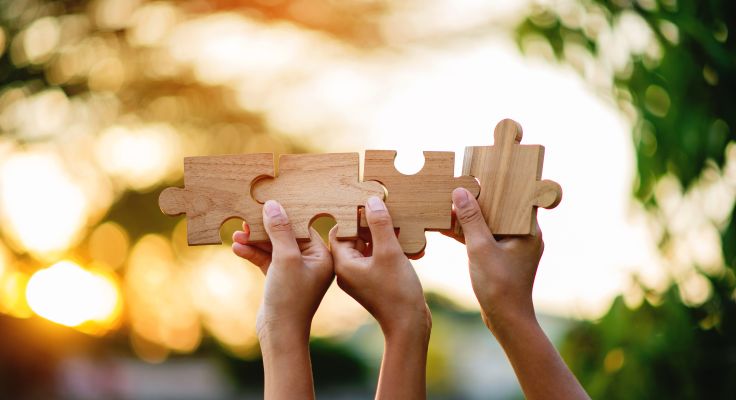 Hände tragen Puzzleteile in die Höhe
