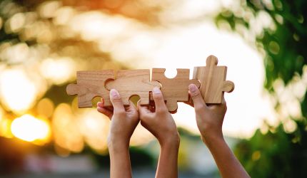 Hände tragen Puzzleteile in die Höhe