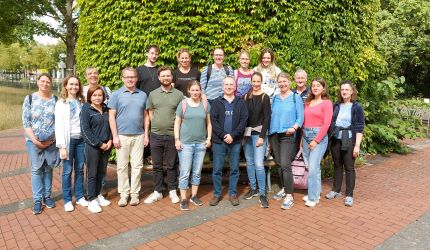 Aufstellung Mitarbeiter:innen vor gruenen Baeumen