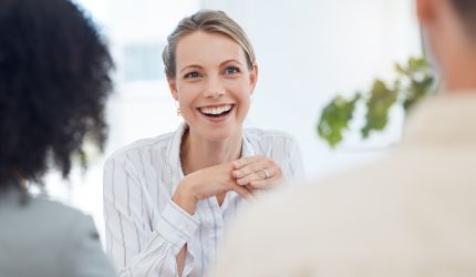 Lächelende Personalmanagerin im Gespräch mit zwei Bewerbern