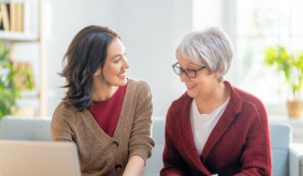 Zwei Frauen sind im Gespräch vor einem Laptop sitzend