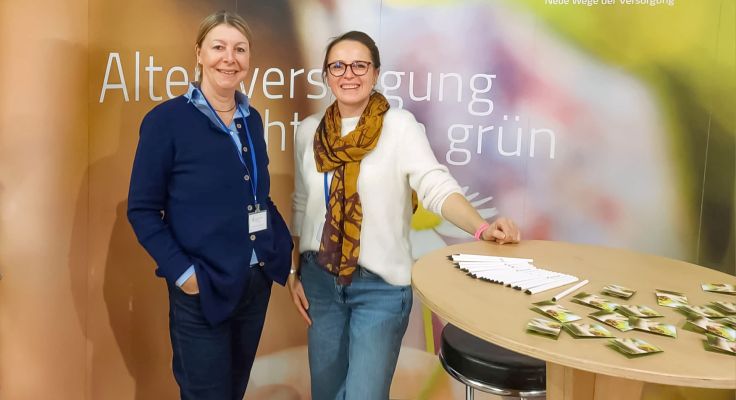 Britta Buchholz und Miriam Jorke stehen vor dem Messestand