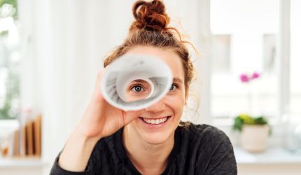 Eine Frau, die durch ein aufgerolltes Stück Papier schaut