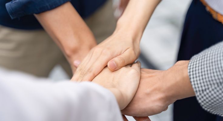Mehrere Hände, die sich in einer unterstützenden Geste ineinander verschränken
