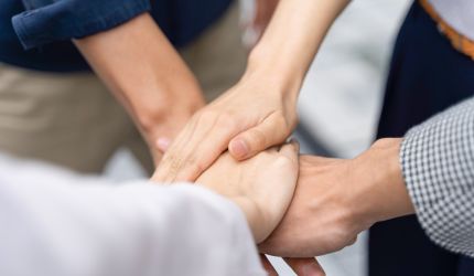 Mehrere Hände, die sich in einer unterstützenden Geste ineinander verschränken