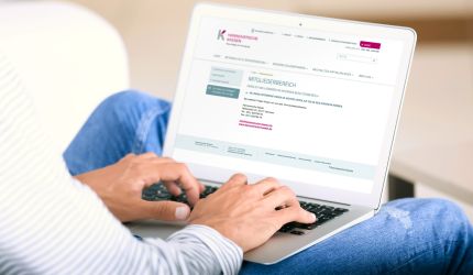 Eine Person sitzt vor geöffnetem Laptop mit Bildschirmanzeige des Mitgliederbereichs der Hannoverschen Kassen
